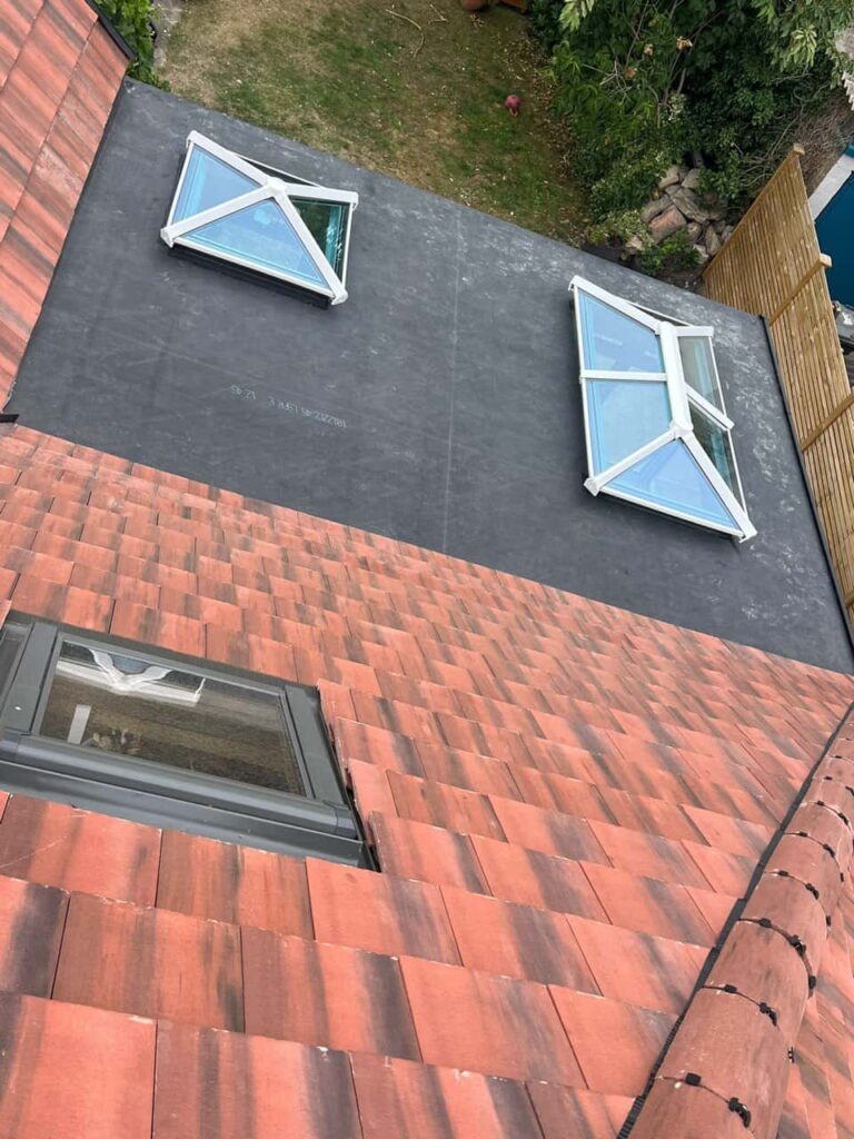 This is a photo taken from the roof ridge looking down a tiled pitched roof on to a flat roof. Works carried out by MCM Roofing Repairs Ringwood